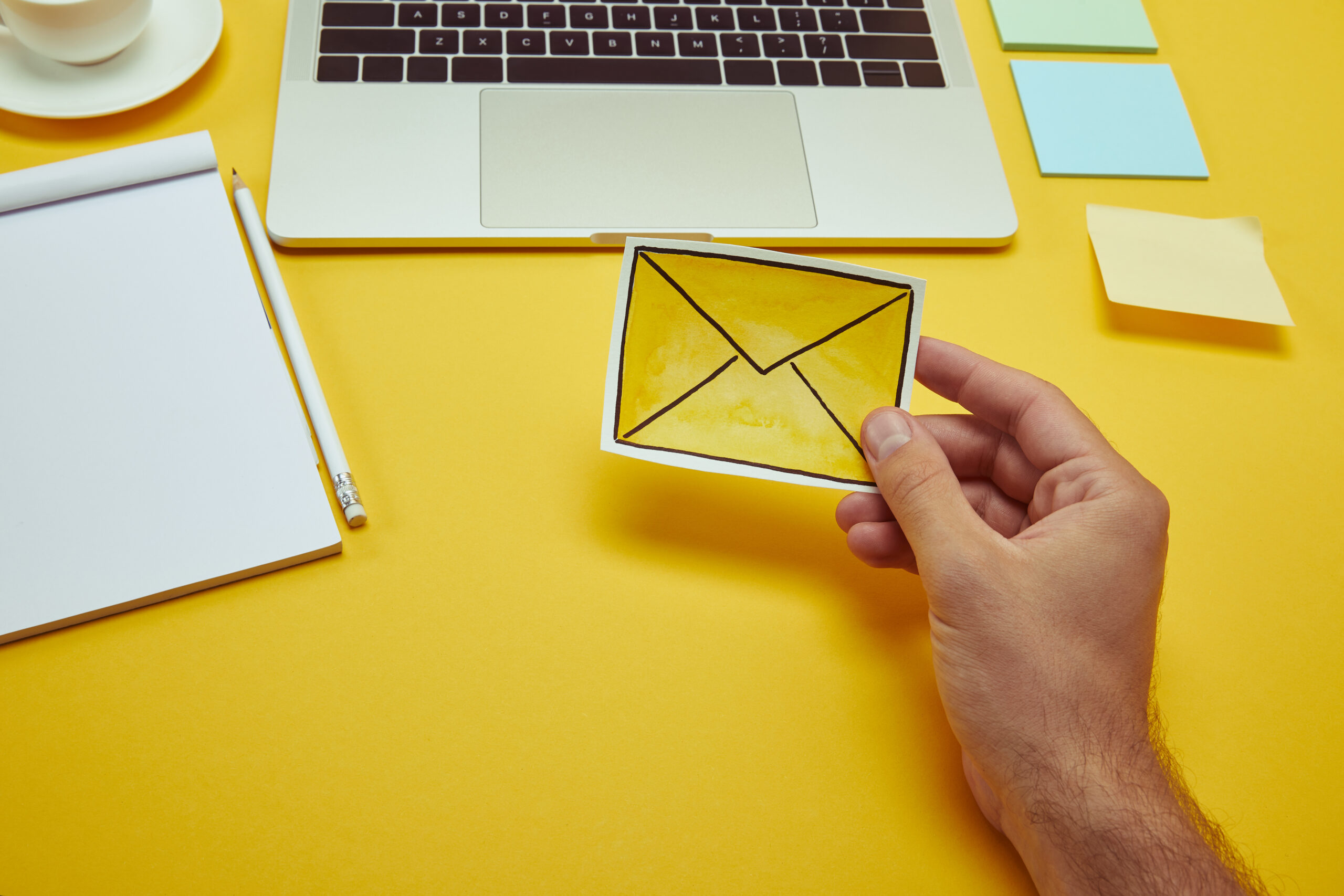 cropped image of man holding envelope sign near laptop