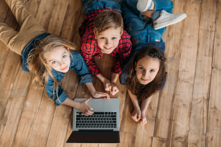 overhead view of little children using digital laptop at home