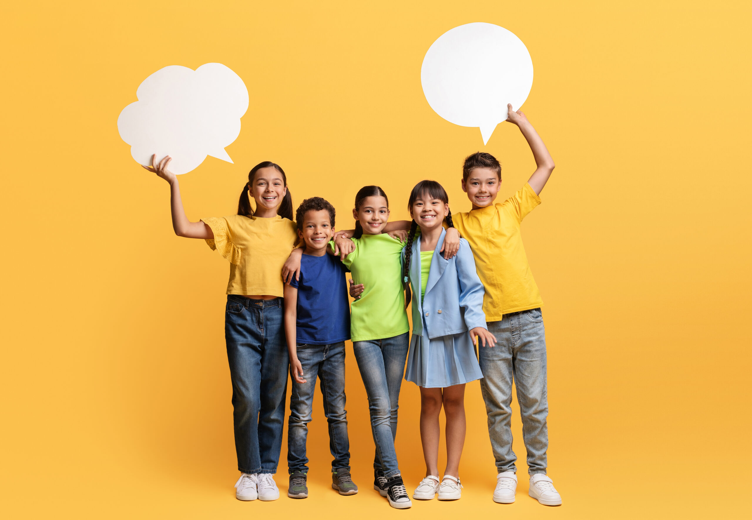 Team of happy school children showing speech balloon paper cards